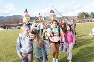 Fourth graders and staff from Jackson Grammar School, Josiah Bartlett Elementary School and Northeast Woodland Chartered Public School walk under the arch of raised ski poles in Schouler Park as part of the "In Memory of Martha" re-enactment and learning projects in North Conway on Nov. 6. 